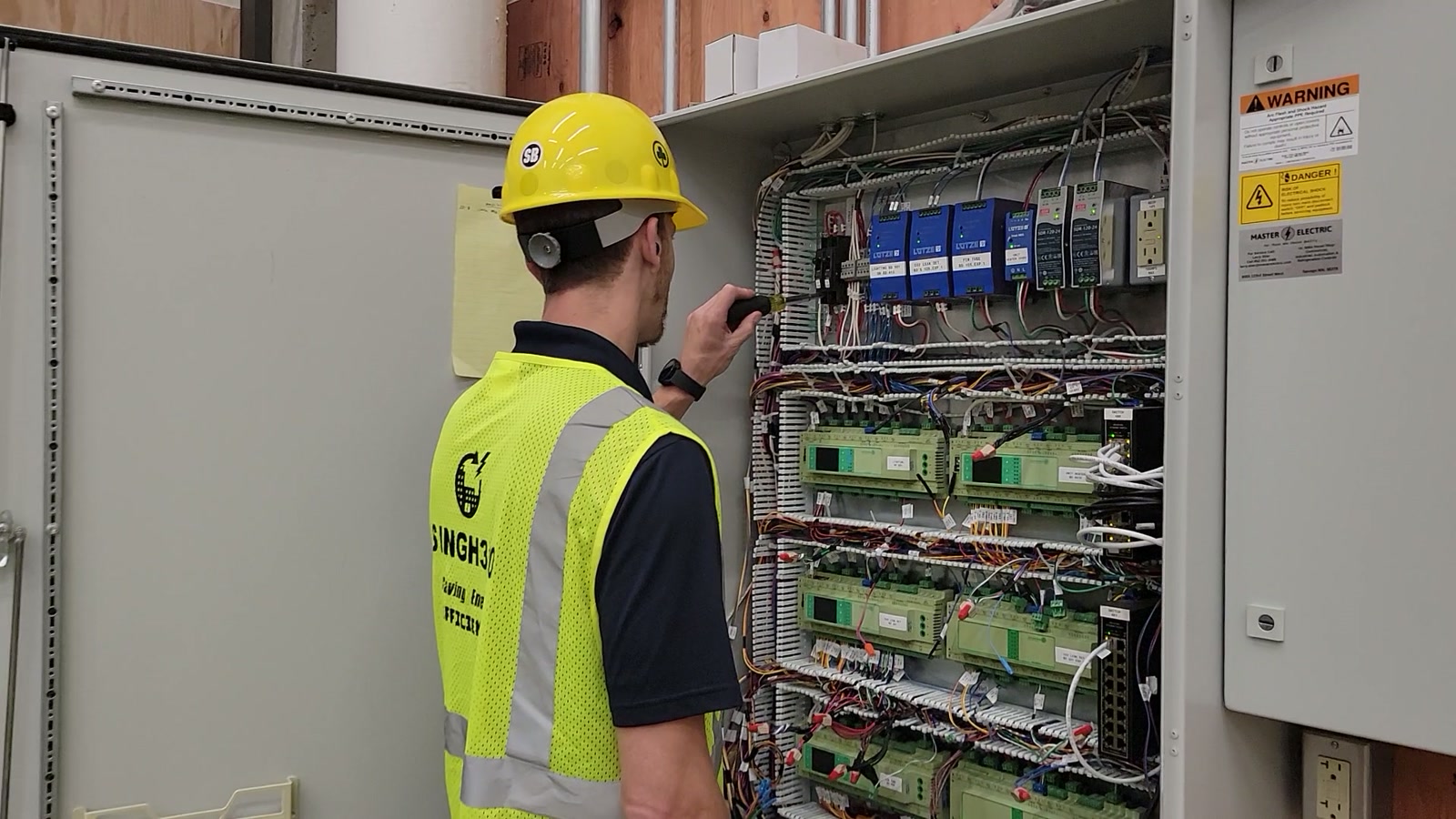 Singh360 technician inspecting controllers and wiring in an EMS and BMS panel